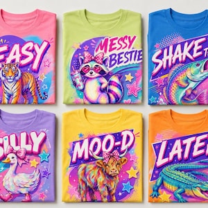 Puede incluir: Seis camisetas coloridas con estampados gráficos: un tigre con el texto EASY, un mapache con MESSY BESTIE, un pez con SHAKE THAT, un pato con SILLY, una vaca highland con MOO-D y un caimán con el texto LATER, todos decorados con estrellas.