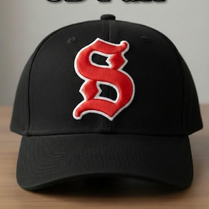 Puede incluir: Gorra de béisbol negra con una letra "S" roja y blanca bordada en la parte delantera. El texto "3D Puff" está encima de la gorra. La parte inferior de la gorra tiene el texto "DST PES JEF EXP VP3 HUS XXX".