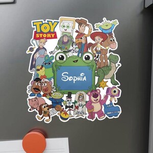 Op de afbeelding: Een rechthoekige magneet met het Toy Story-logo en een collage van diverse animatiefiguren rondom een centraal groen, kikker-vormig kader. De naam Sophia is in witte schrijfletters in het midden van het blauwe vlak gedrukt.