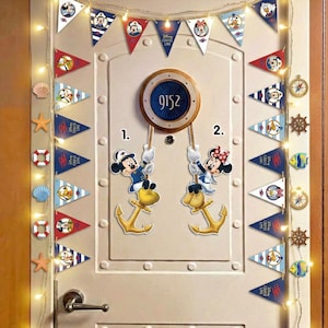 Könnte beinhalten: Eine weiße Tür, verziert mit Wimpelfahnen im Disney Cruise Line-Design, Mickey- und Minnie-Mouse-Ausschnitten und nautischen Akzenten. Ein kreisförmiges Türnummernschild zeigt "9152". Dekorative Lichter und nautische Ornamente vervollständigen den festlichen Look.