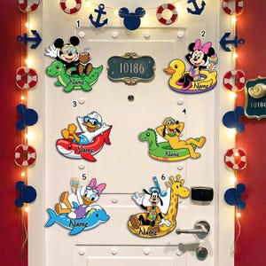 May include: A white door decorated with Disney character cutouts, including Mickey Mouse, Minnie Mouse, Donald Duck, Pluto, and Daisy Duck, on inflatable floats. The door also features nautical-themed decorations and a house number plaque.