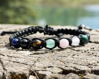 May include: A black cord bracelet featuring a row of seven smooth, round gemstone beads in various colors, including blue, black, brown, light green, pink, white, and dark green, secured with a woven macrame-style knotting technique.