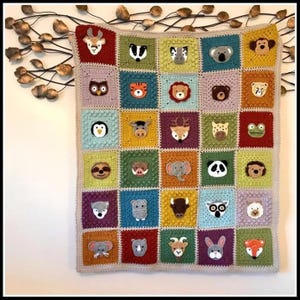 May include: A colorful, square crochet blanket featuring a variety of animal faces. Each animal is centered in a different colored square, including a deer, badger, zebra, koala, monkey, owl, tiger, lion, bear, and more. The blanket is trimmed with a light gray border.