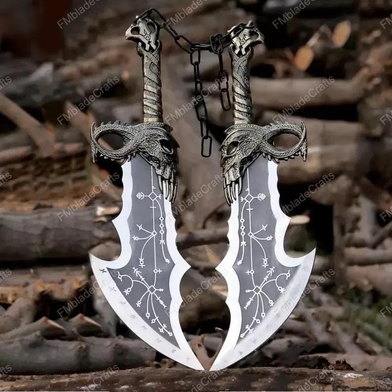 May include: A pair of silver fantasy blades with detailed skull-shaped handles and a connecting chain. The blades feature a distinctive curved shape and etched patterns. The background is a blurred arrangement of wooden logs. Each blade is approximately 40 cm long.
