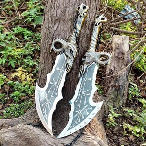 May include: Two decorative swords with silver-coloured blades and ornate handles. The handles feature a skull design, and the blades have intricate patterns. The swords are leaning against a tree trunk, with a chain visible.