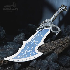 May include: A fantasy sword with a blue and white blade. The hilt and guard have detailed silver-coloured dragon and skull designs. The blade features white markings. The text "Vikings Blade" is visible on the image.