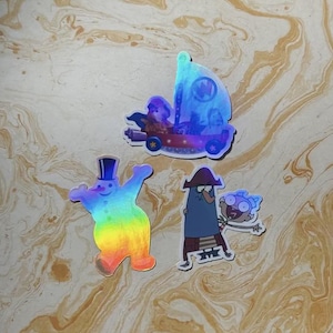 May include: Three holographic stickers featuring cartoon characters. One sticker shows a red vehicle with a sail, another is a rainbow-colored snowman wearing a top hat, and the third depicts two animated figures, one tall and one small.