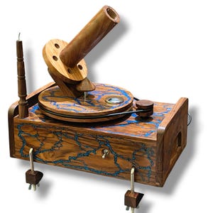 Pode incluir: Um gramofone de madeira artesanal com um design único. O gabinete de madeira apresenta detalhes em resina azul, uma plataforma giratória e um alto-falante em forma de chifre. O gramofone tem uma estética vintage com um toque moderno, mostrando artesanato intrincado.