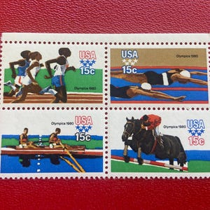 Peut inclure: Un bloc de quatre timbres-poste olympiques américains de 1980, chacun marqué 15c. Les timbres présentent des illustrations de coureurs, nageurs, rameurs et un cavalier. Chaque timbre inclut le texte USA, 15c et Olympics 1980 en diverses couleurs.