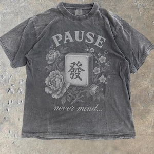 May include: A charcoal gray short-sleeve t-shirt featuring a graphic print of a mahjong tile with the Chinese character for green dragon, surrounded by floral illustrations. The text PAUSE is printed above and never mind... below the tile.
