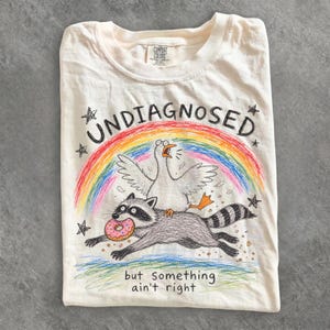 Odiagnostiserad men något stämmer inte T-shirt, rolig gåsridning tvättbjörn T-shirt, bekväma färger fåniga gås T-shirt, mental hälsa humor gåva