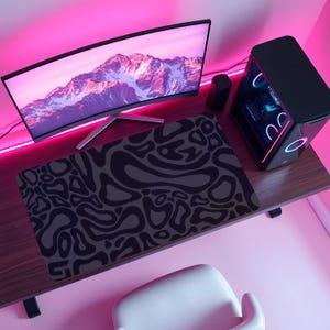 May include: A black and gray patterned mousepad sits on a wooden desk, with a curved monitor displaying a mountain scene. A black computer tower with colorful lights is to the right. The room is lit with pink ambient lighting.