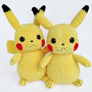 Pode incluir: Dois brinquedos de pelúcia Pikachu amarelos feitos à mão. Cada pelúcia tem olhos pretos, bochechas vermelhas e orelhas com pontas pretas. Os brinquedos são feitos de crochê com um fio macio e texturizado e têm braços e pernas pequenos. O fundo é branco liso.