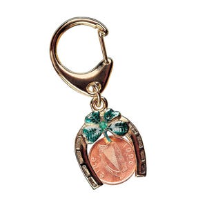 May include: Gold horseshoe keychain with a green shamrock and a copper Irish coin with the year 1996 and a harp design.