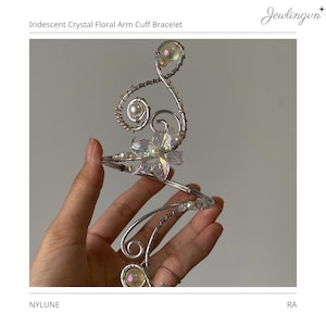 May include: An arm cuff bracelet featuring silver-toned wire swirls, iridescent crystal floral accents, and small white pearls. The design includes the text Iridescent Crystal Floral Arm Cuff Bracelet, Jewlingun, and NYLUNE RA.