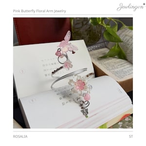 May include: A silver arm cuff with pink floral and butterfly accents. The jewelry features a delicate design with pink flowers and a butterfly. The text "Pink Butterfly Floral Arm Jewelry" is visible.
