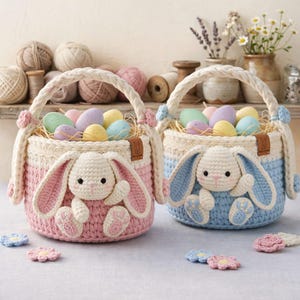 Może przedstawiać: Dwa szydełkowe koszyki wielkanocne, jeden różowy i jeden niebieski, każdy z królikiem. Koszyki wypełnione są kolorowymi pisankami i mają sznurkowe uchwyty. Szydełkowe kwiaty zdobią koszyki.