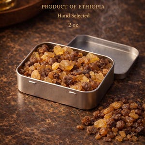 Puede incluir: Una lata de metal abierta llena de incienso y mirra, con el texto "FRANKINCENSE & MYRRH" y "PRODUCT OF ETHIOPIA". La lata revela la resina aromática. Un pequeño montón de resina está al lado. El producto es de 57 gramos.