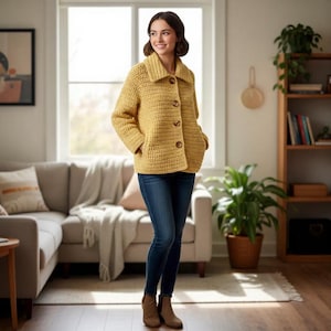 May include: A mustard yellow crochet jacket with a collared neckline and wooden buttons. The jacket has two front pockets and is worn with blue jeans and brown boots. The jacket is a medium weight and appears to be handmade.