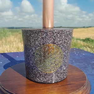 Peut inclure: Un bol chantant en cristal violet et argenté, orné d'un motif géométrique doré. Il repose sur une base en bois et possède une tige cuivrée. Le fond présente un ciel bleu et un champ de blé.