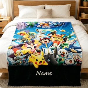May include: A blue blanket featuring a colorful illustration of various cartoon characters. The blanket has a black border with the word "Name" in white script. The blanket is spread across a bed with white bedding.