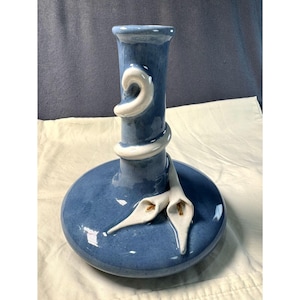 Può includere: Un vaso di ceramica blu con accenti di calle bianche. Il vaso ha una base rotonda e un collo cilindrico, con un design bianco a spirale attorno al collo. Due calle bianche sono attaccate alla base.