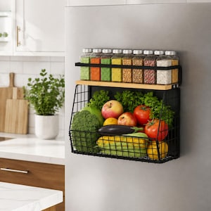 May include: A black metal magnetic storage rack with a light wood shelf top. The top shelf holds eight clear glass spice jars with silver lids. The bottom wire basket contains fresh produce including broccoli, apples, tomatoes, and corn.
