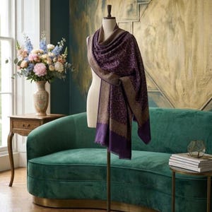 Peut inclure: Un châle violet profond drapé sur un mannequin, présentant un motif floral répétitif et complexe dans une teinte plus claire. Le châle possède une large bordure de couleur unie dans un ton doré sourd qui encadre le motif détaillé.