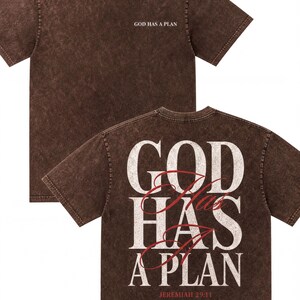 A brown t-shirt with the text "GOD HAS A PLAN" printed on the back in white and red lettering.