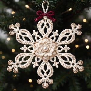 May include: A cream-colored crocheted snowflake ornament featuring intricate lace-like patterns, metallic gold thread accents, a central white pearl bead, and a small dark red bow at the top loop for hanging on a tree branch.