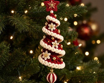 Puede incluir: Un adorno de árbol de Navidad en forma de espiral, tejido a ganchillo en hilo rojo oscuro con bordes festoneados de color crema. El árbol está decorado con pequeñas cuentas doradas y flores blancas, rematado con una estrella roja y una bola.
