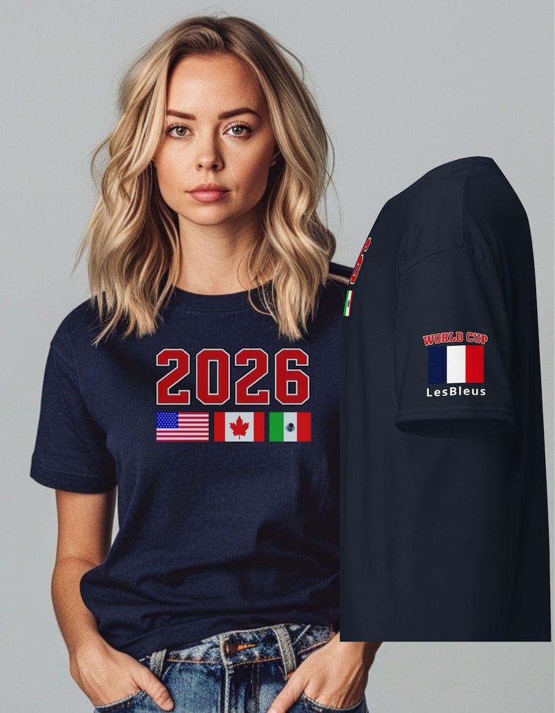 May include: Navy blue t-shirt with the number "2026" in red and white, along with the flags of the United States, Canada, and Mexico. The sleeve features the text "WORLD CUP" and the words "Les Bleus" with the French flag.
