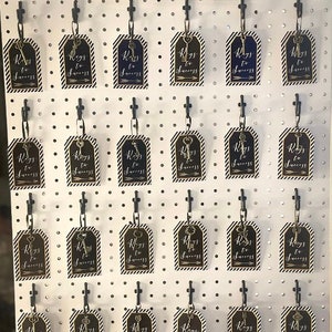 Puede incluir: Un tablero de clavijas blanco con ganchos negros que sostienen etiquetas doradas en forma de llave con el texto "Keys to Success" en cada etiqueta. El tablero de clavijas tiene un letrero encima que dice "Key for Success - Grab a Tag - Use a Pen - Leave Your Advice - Thank You".