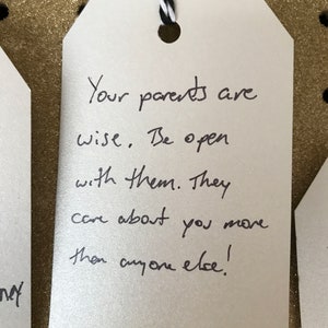 Puede incluir: Una etiqueta blanca con texto escrito a mano en negro que dice "Tus padres son sabios. S&eacute; abierto con ellos. Se preocupan por ti m&aacute;s que nadie!"