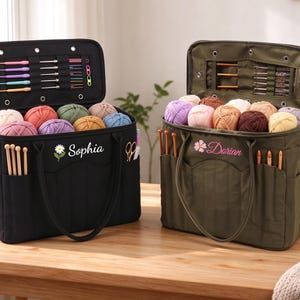 May include: Two rectangular yarn storage bags, one black and one olive green, each featuring an open lid with internal elastic loops for crochet hooks, exterior pockets for knitting needles, and yarn balls inside. The bags are embroidered with the names Sophia and Darian.