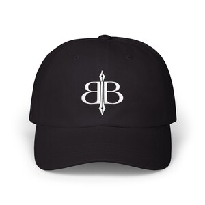 May include: Black baseball cap with a curved brim. The cap features a white embroidered logo of two mirrored "B" letters with a vertical line through the center. The hat is made of a soft, durable fabric.