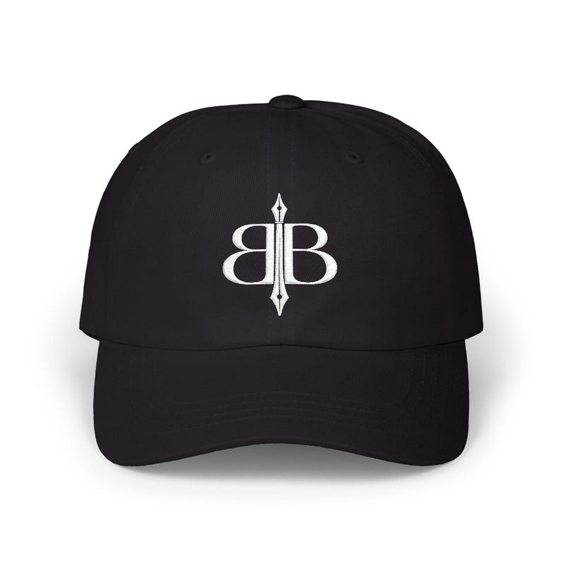May include: Black baseball cap with a curved brim. The cap features a white embroidered logo of two mirrored "B" letters with a vertical line through the center. The hat is made of a soft, durable fabric.