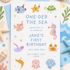 May include: A birthday invitation with a sea theme. The invitation features colorful cartoon sea creatures and the text "ONE-DER THE SEA" and "JAKE'S FIRST BIRTHDAY". Decorative seashells and starfish surround the invitation.