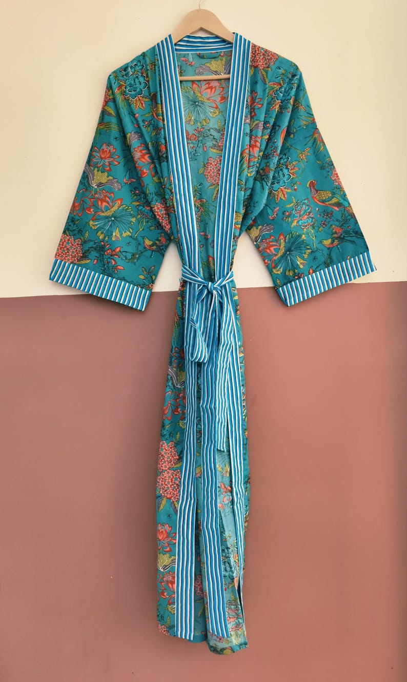 May include: A teal kimono robe featuring a vibrant floral and bird print in shades of orange, yellow, and green. The garment includes a white and teal vertical striped trim along the front opening, sleeve cuffs, and a matching tie-waist belt.