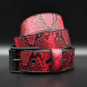 May include: A coiled belt featuring a vibrant red and black snakeskin pattern. The belt includes a matte black buckle with the word LOWLIFE embossed vertically on the frame, along with matching black metal eyelets and a black belt loop.