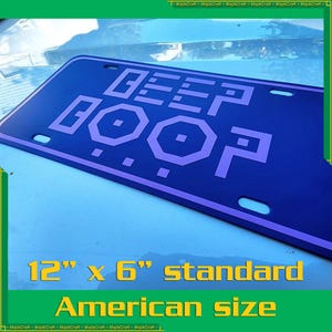 May include: A blue metal license plate with a white border and the text "DEEP BOOP" in purple. The plate is 12 inches by 6 inches, standard American size.