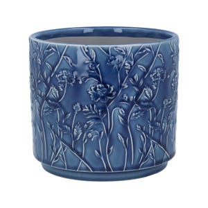 Op de afbeelding: Een blauwe keramische bloempot met een gedetailleerd bloemenreliëfpatroon. De pot heeft een cilindrische vorm met een licht uitlopende basis en een gladde binnenkant. Het reliëfontwerp toont verschillende bloemen en bladeren.