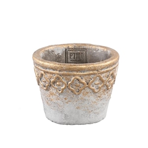May include: A small, round, grey concrete planter with a textured, weathered finish. The rim features a raised, gold-painted decorative pattern of repeating four-petaled shapes. The interior wall displays a square stamp with the text PTMD.
