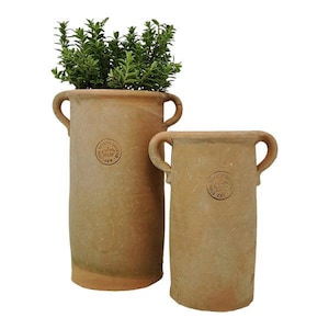 Könnte beinhalten: Zwei zylindrische Pflanzgefäße in Terrakotta-Farbe mit gebogenen Griffen. Ein Pflanzgefäß enthält grüne Blätterpflanzen. Jedes Pflanzgefäß hat ein rundes Emblem. Die Pflanzgefäße sind unterschiedlich groß.