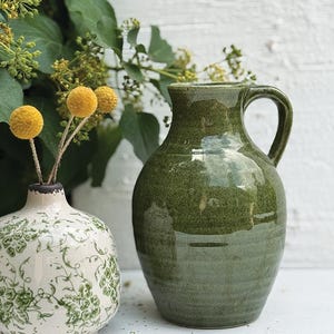 May include: A set of three ceramic mugs with a speckled, matte finish. The mugs are in shades of cream, light gray, and dark gray. Each mug has a simple, minimalist design, perfect for coffee or tea.