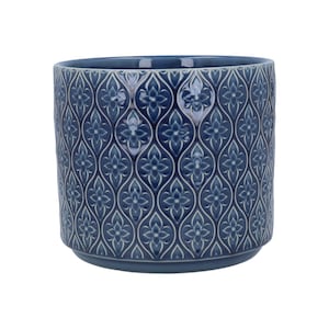 May include: A blue ceramic plant pot with a repeating floral pattern. The pot has a cylindrical shape and a slightly flared base. The raised floral design is in a lighter shade of blue, creating a textured appearance. Suitable for indoor or outdoor use.