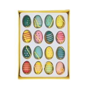 May include: A set of twelve decorative Easter eggs in a yellow box. The eggs are painted with diverse patterns, including stripes and polka dots, in shades of green, pink, yellow, and blue. Each egg has a yellow string attached.