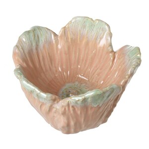 May include: A ceramic bowl shaped like a flower, with a soft pink interior and a light green rim. The bowl has a textured surface, and the petals are slightly ruffled. The overall design is organic and elegant.