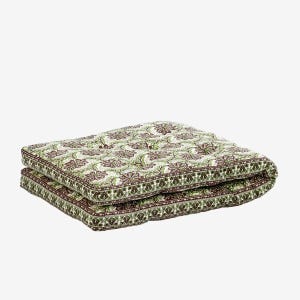 May include: Two folded square cushions with a floral pattern. The cushions feature a repeating design of green leaves and maroon flowers on a white background. The edges are trimmed with a dark brown border.