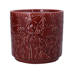 Peut inclure: Un pot de fleurs en céramique bordeaux profond avec une finition brillante et un motif en relief de fleurs sauvages, de tiges et de feuilles couvrant toute la surface extérieure. Le récipient cylindrique a une base plate et un bord supérieur large.